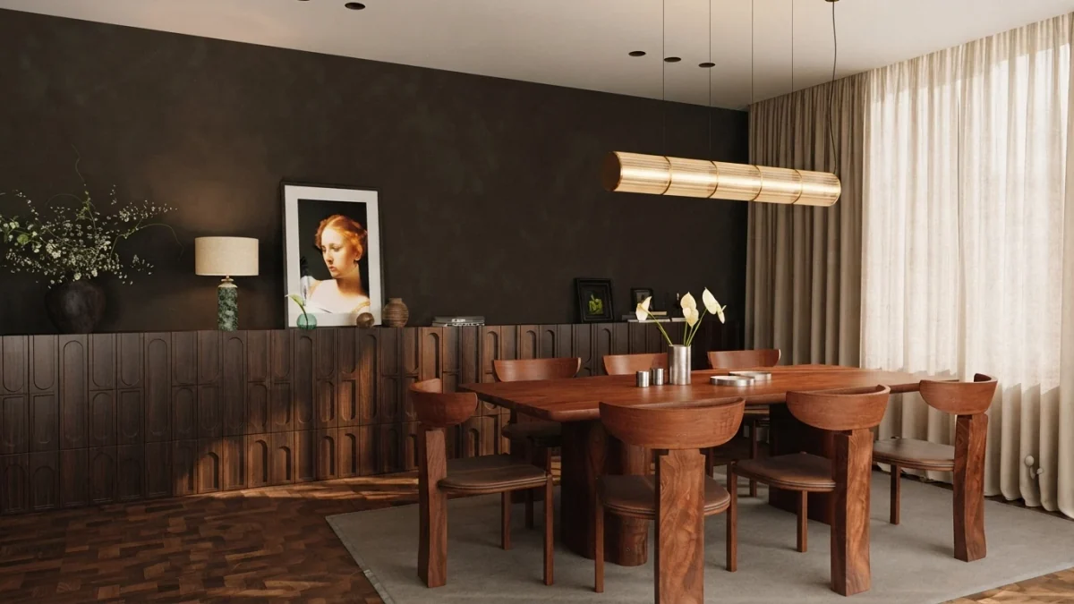 Moody dining room with a dark wall, a long fluted walnut sideboard, a solid timber table and one small framed portrait of a woman leaning on the sideboard beside a lamp and a vase