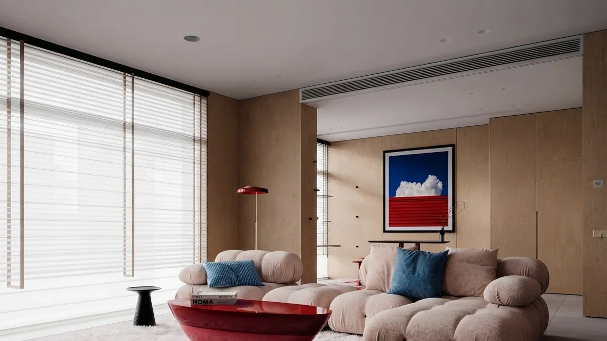 Warm timber panelled apartment living room with a wide beige modular sofa, a red coffee table and one bold graphic print of a cloud over a red horizon centred on the right section of the sofa